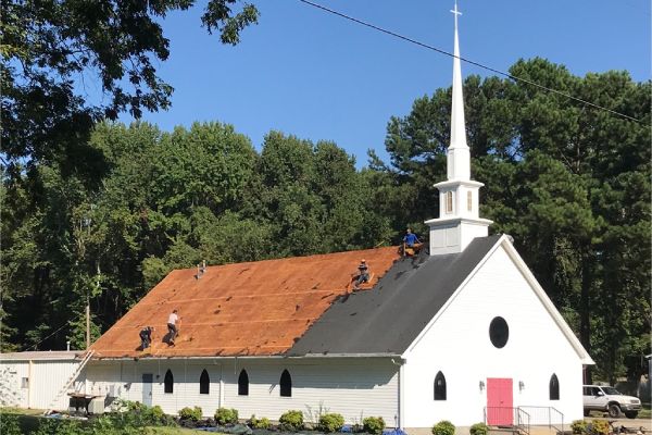 A church with two men working on the roof.