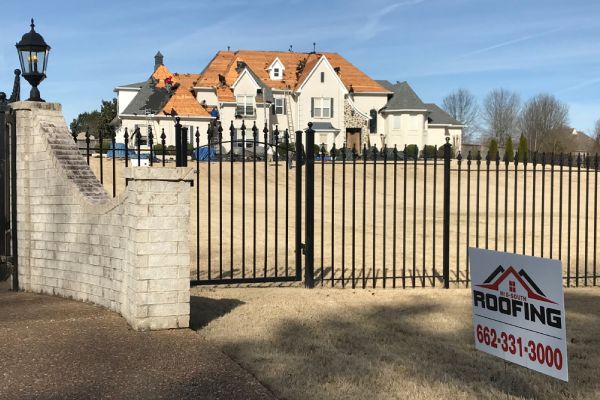 A gated driveway with a house in the background.