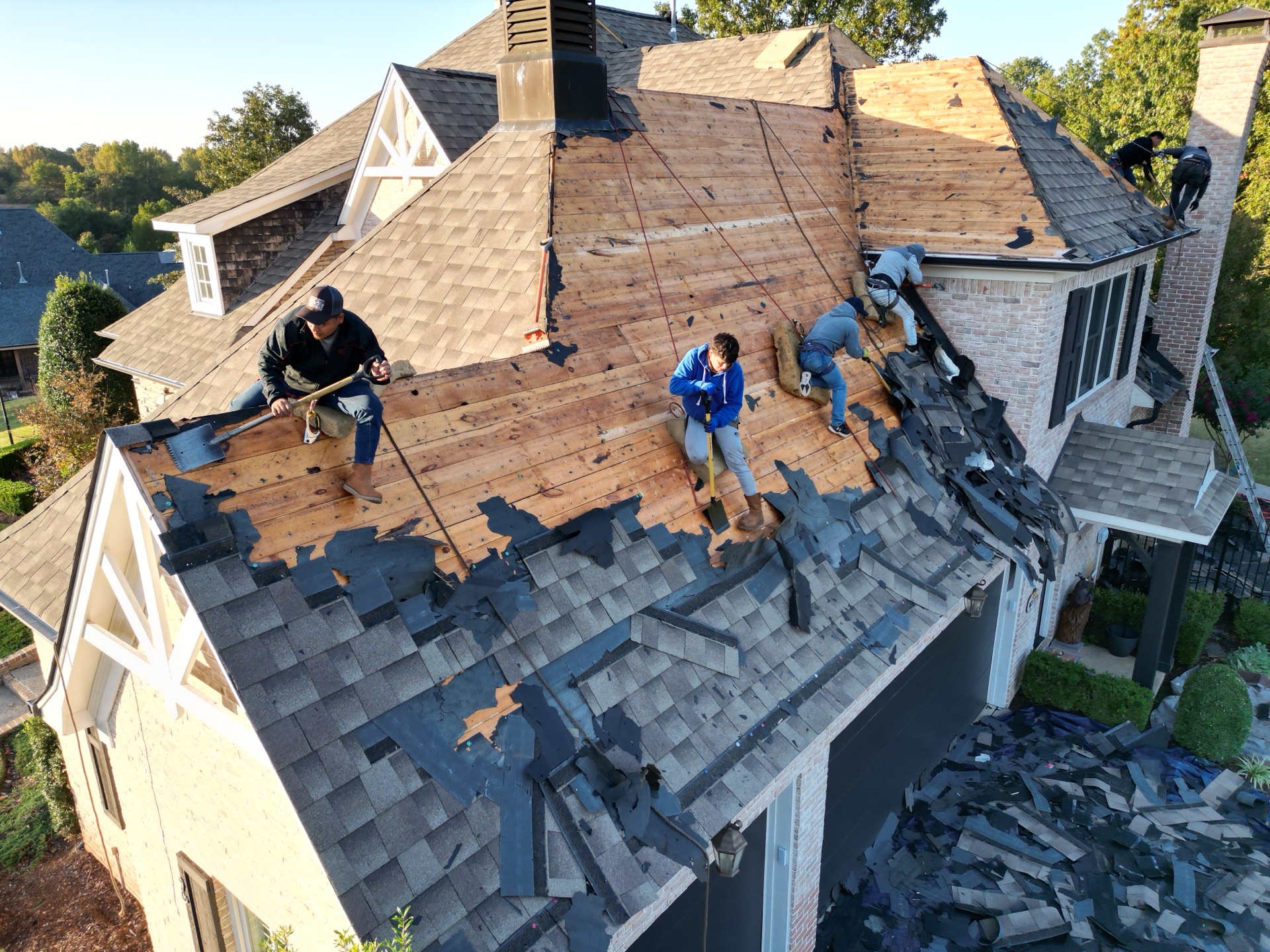 Ultimate Roofing crew actively replacing a roof on a large home
